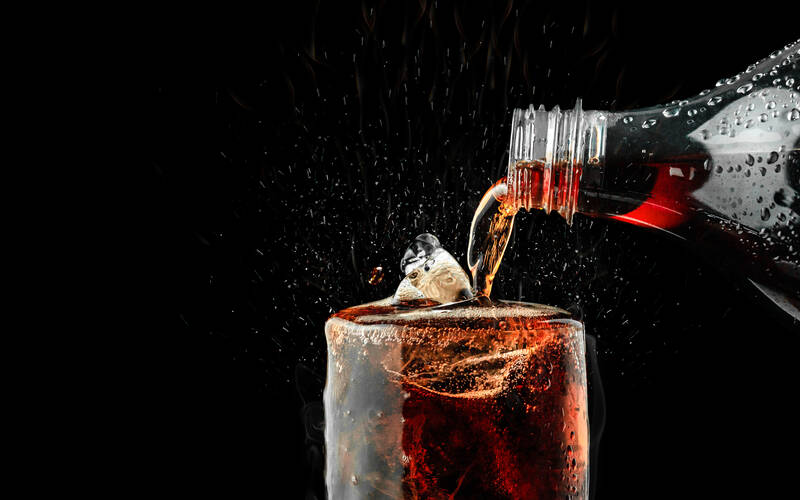 cola soft drink being poured into a glass
