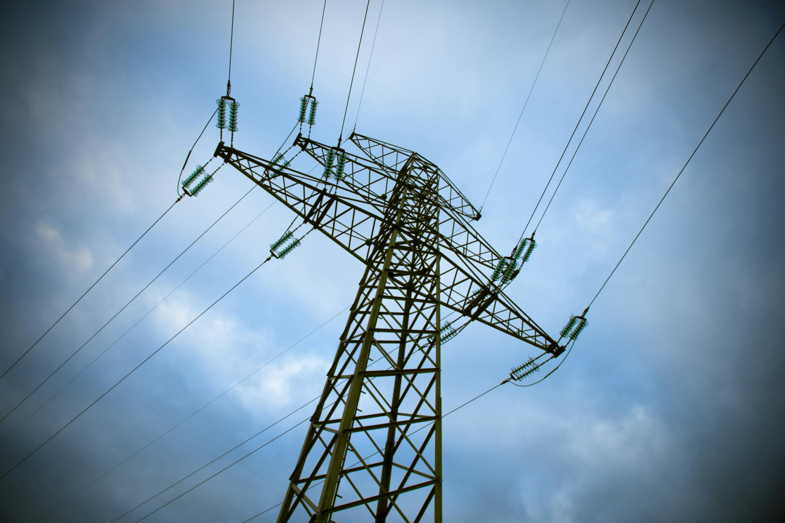 A majestic transmission tower stands tall against a cloudy blue sky, showcasing modern electric infrastructure.