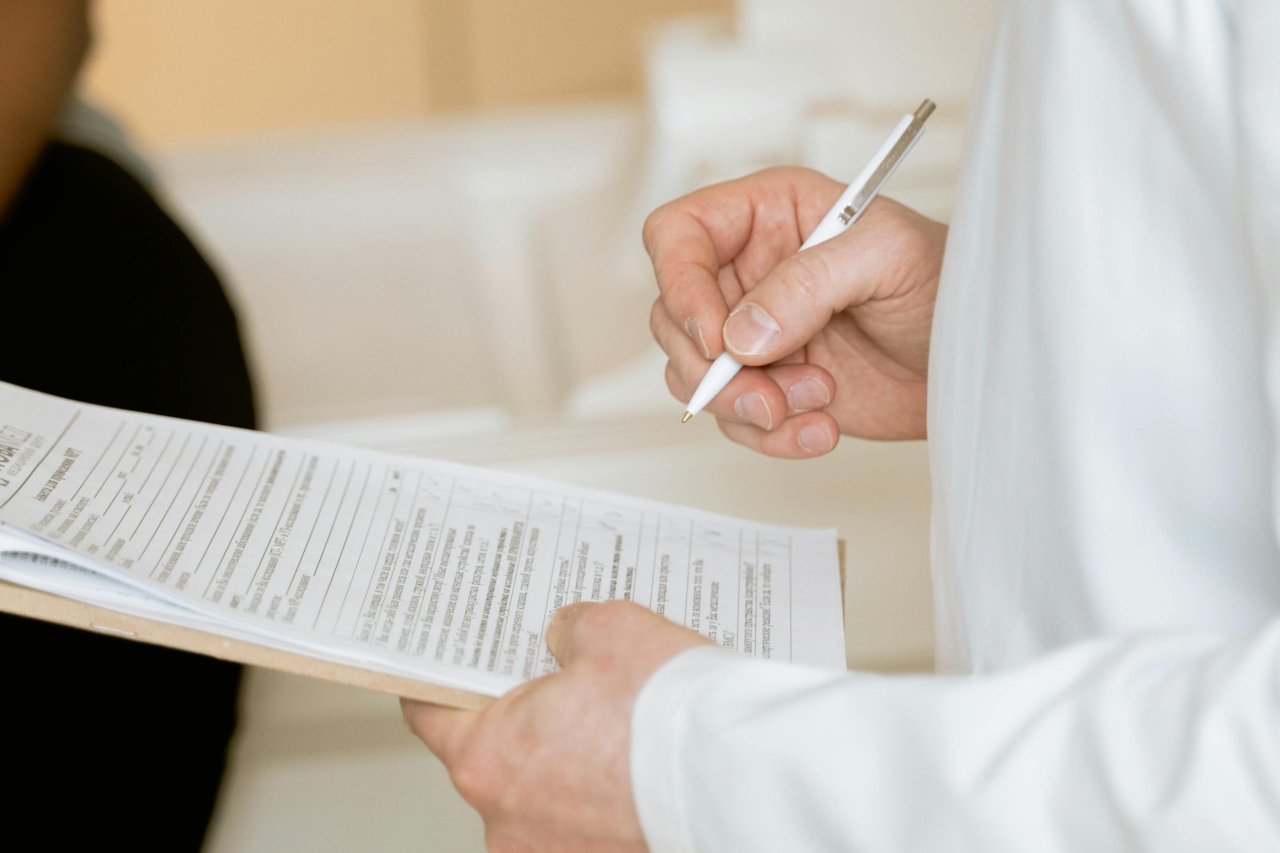 A medical professional in a white coat examines a clipboard with patient documents.