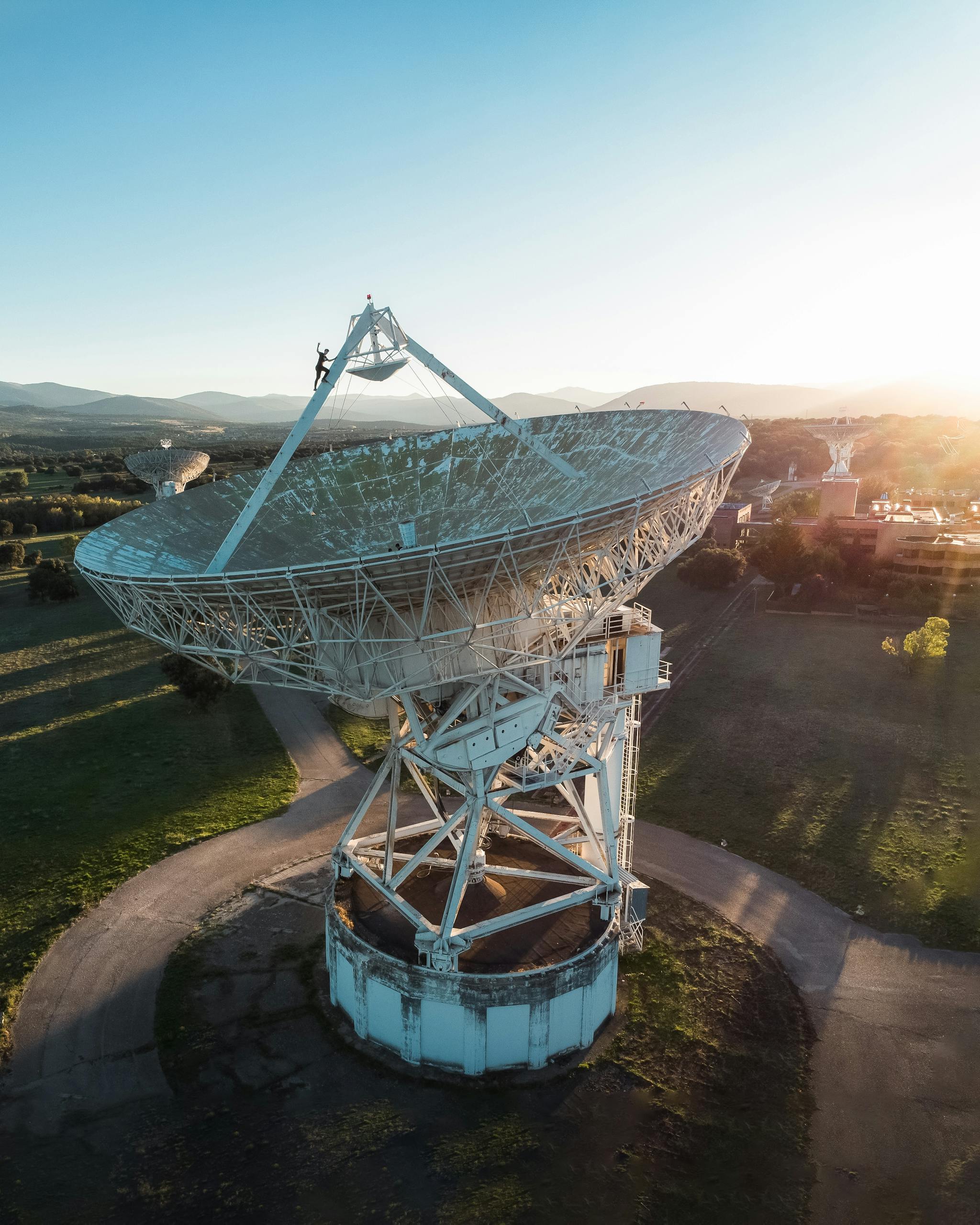 A towering satellite dish in a field at sunrise, highlighting technology and exploration.