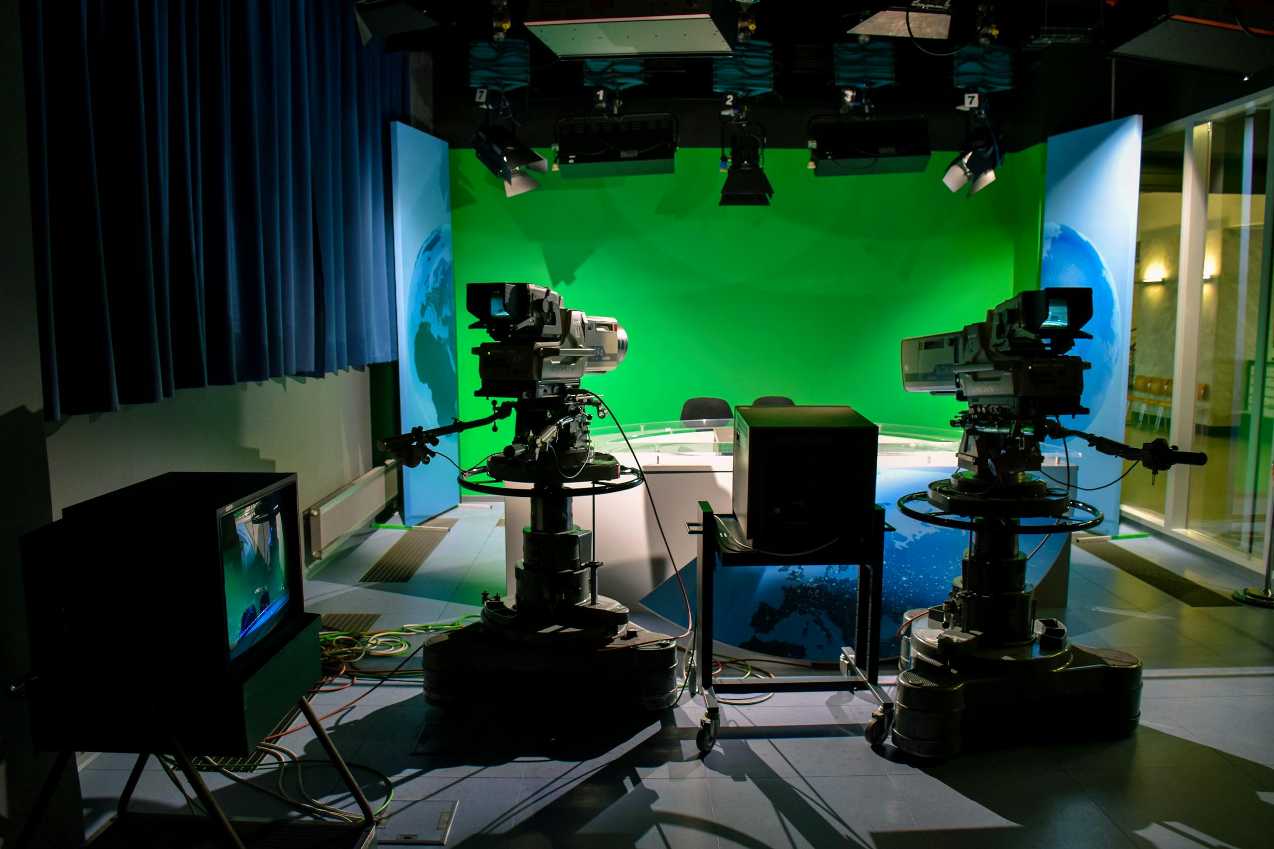 A TV studio setup featuring cameras and a green screen for production purposes.