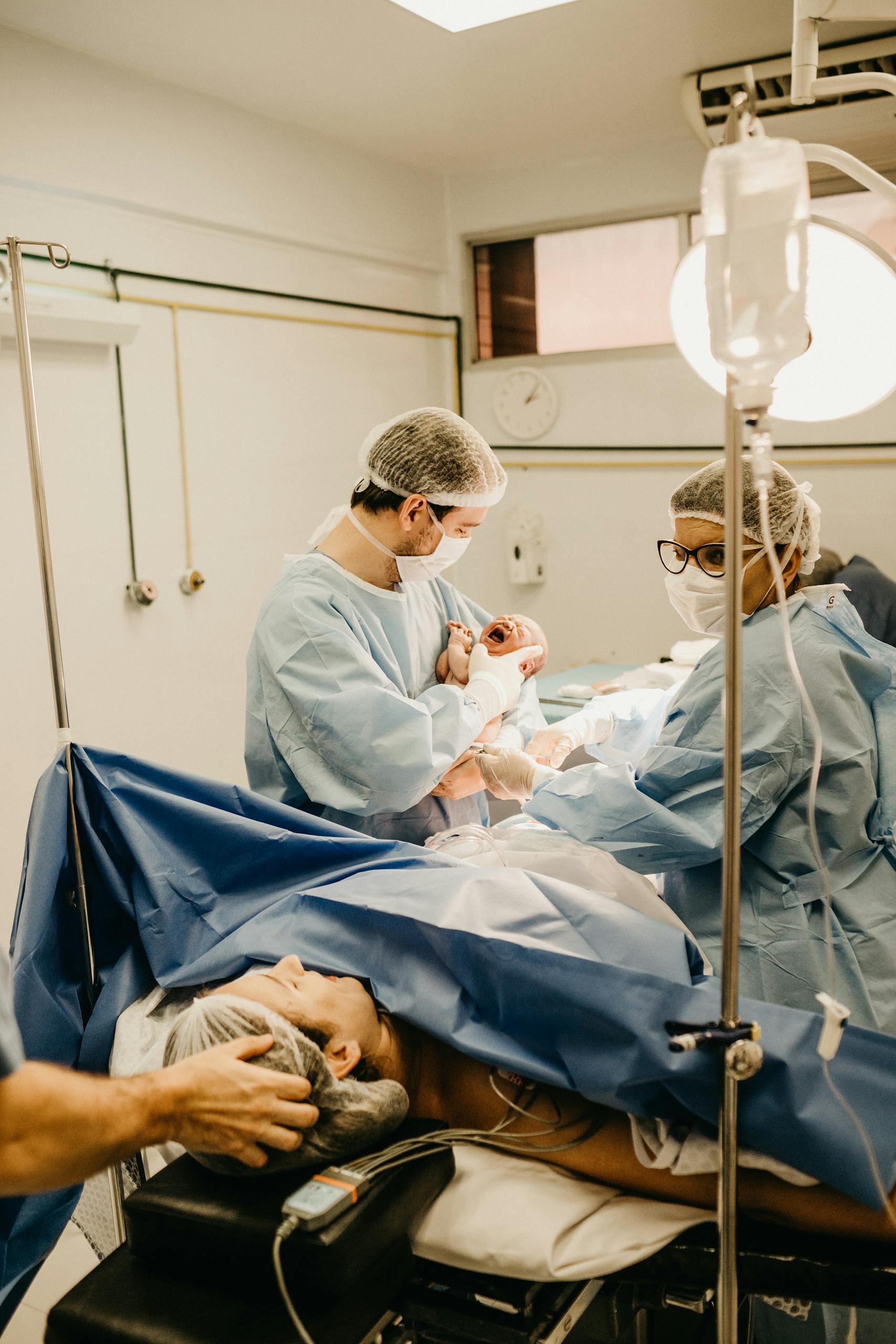 Medical professionals delivering a newborn in an operating room, showcasing teamwork and care.