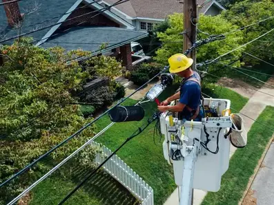 Electrical technician in a yellow hard hat working on power lines