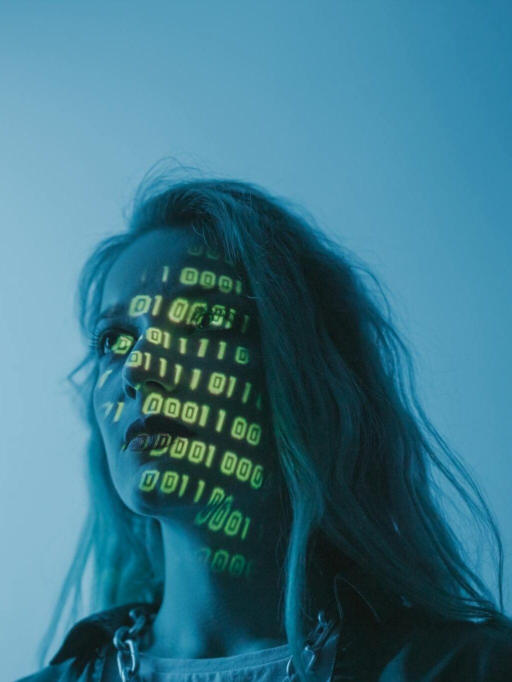 A woman with binary code lights projected on her face, symbolizing technology.