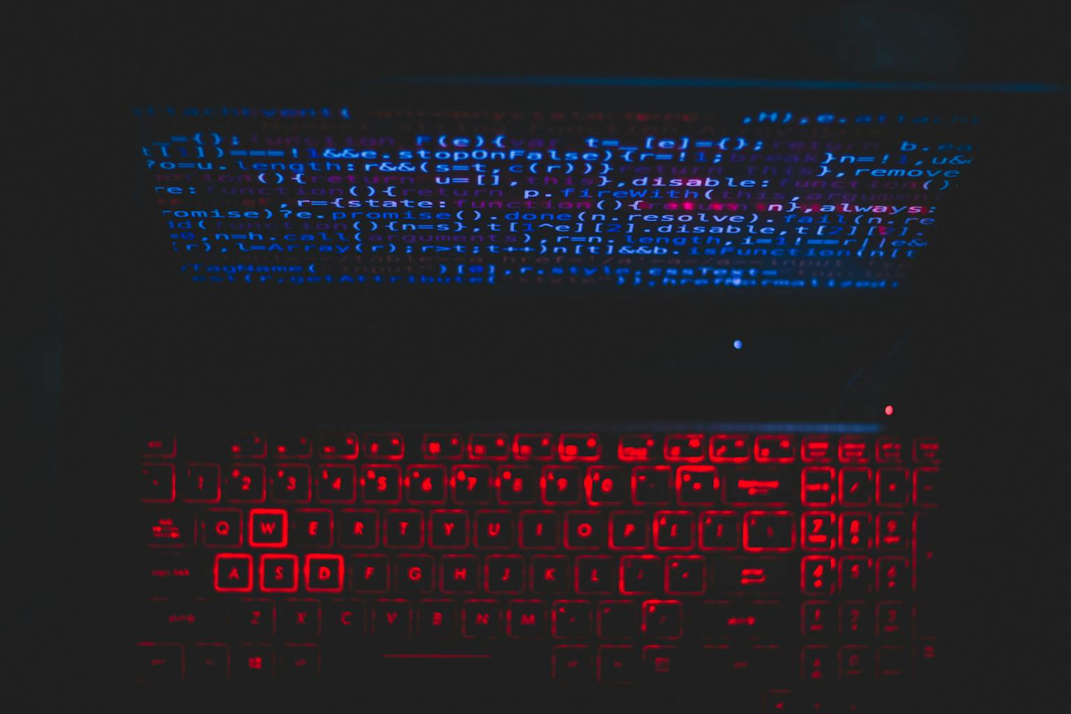 Dark-themed pentest laptop setup with a red glowing keyboard and code on screen, ideal for tech enthusiasts.