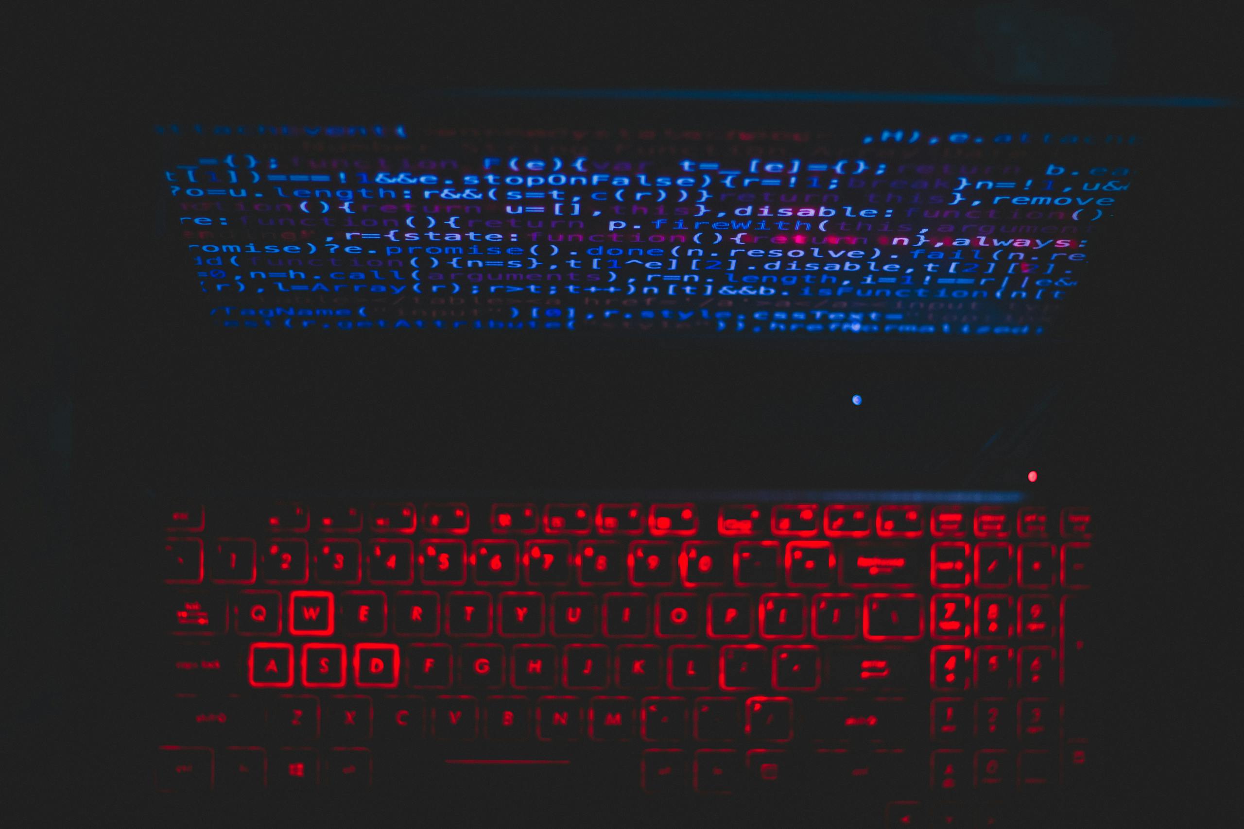 Dark-themed pentest laptop setup with a red glowing keyboard and code on screen, ideal for tech enthusiasts.