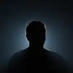 A silhouette of a mysterious figure illuminated by backlight, creating a dramatic and moody effect.